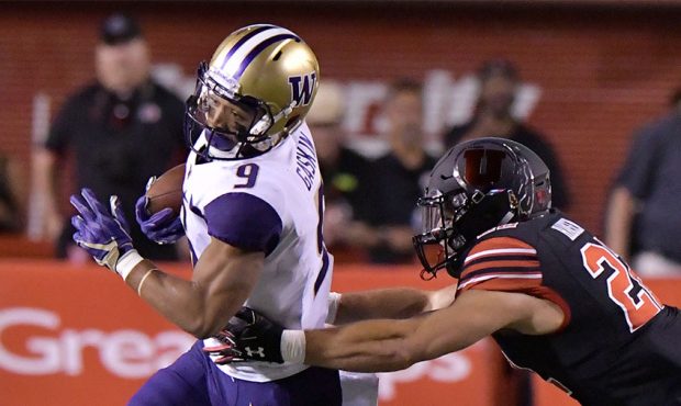 Myles Gaskin #9 of the Washington Huskies tries to avoid the tackle by Chase Hansen #22 of the Utah...