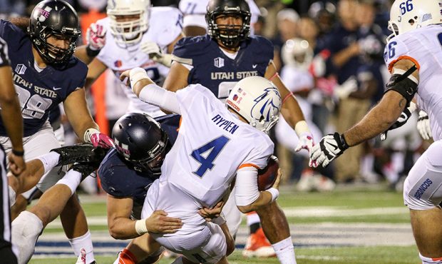 Quarterback Brett Rypien #4 of the Boise State Broncos is sacked by a host of Utah State Aggies def...