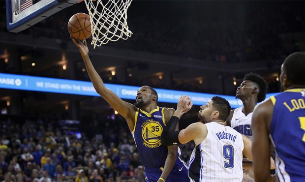 Kevin Durant #35 of the Golden State Warriors shoots over Nikola Vucevic #9 and Jonathan Isaac #1 o...