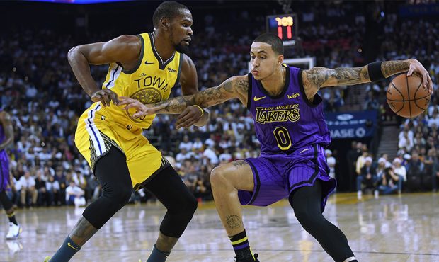 Kyle Kuzma #0 of the Los Angeles Lakers dribbles the ball while being closely guarded by Kevin Dura...