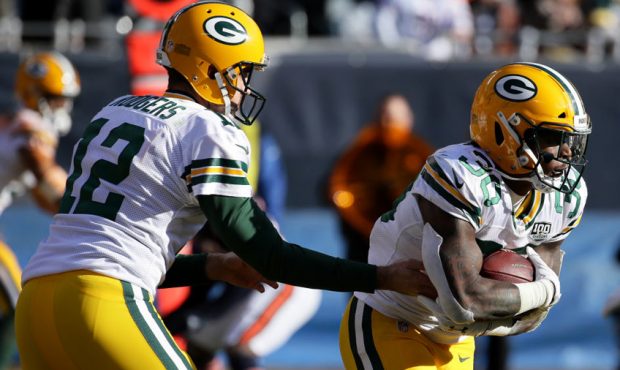 Quarterback Aaron Rodgers #12 of the Green Bay Packers hands the football off to Jamaal Williams #3...