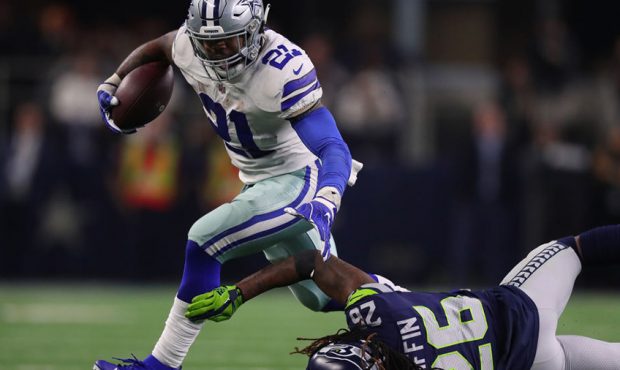 Ezekiel Elliott #21 of the Dallas Cowboys breaks a tackle attempt by Shaquill Griffin #26 of the Se...