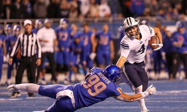 Running back Lopini Katoa #4 of the BYU Cougars pushes off of linebacker Curtis Weaver #99 of the B...