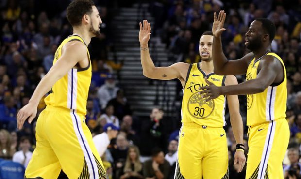 Stephen Curry #30 and Draymond Green #23 of the Golden State Warriors congratulate Klay Thompson #1...