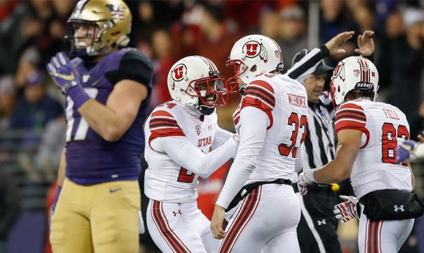 Mitch Wishnowsky #33 of the Utah Utes is congratulated by Kenric Young #24 after recovering an on-s...