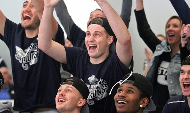 Utah State guard Sam Merrill, center, and his teammates react as the Aggies' berth in the NCAA Tour...