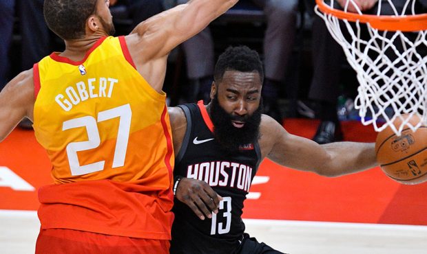 James Harden #13 of the Houston Rockets looks to pass around Rudy Gobert #27 of the Utah Jazz in th...