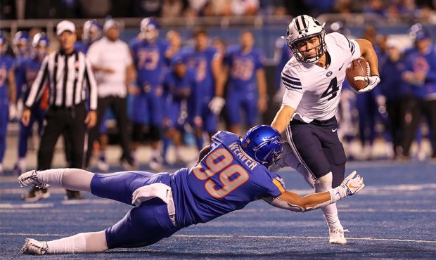 Running back Lopini Katoa #4 of the BYU Cougars pushes off of linebacker Curtis Weaver #99 of the B...
