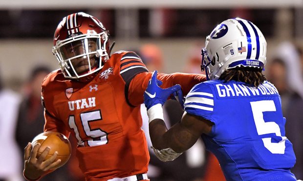 Quarterback Jason Shelley #15 of the Utah Utes runs with the ball and stiff arms Dayan Ghanwoloku #...