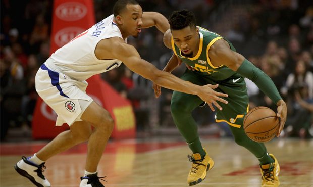 Avery Bradley #11 of the Los Angeles Clippers defends agains the dribble of Donovan Mitchell #45 of...