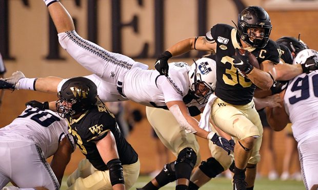 David Woodward #9 of the Utah State Aggies dives to tackle Cade Carney #36 of the Wake Forest Demon...