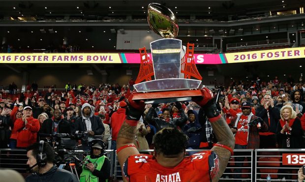 Isaac Asiata #54 of the Utah Utes holds the trophy up to the crowd after a win against the Indiana ...