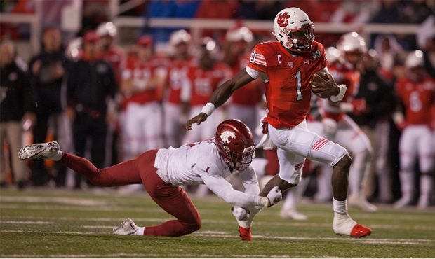 Tyler Huntley #1 of the Utah Utes breaks a tackle attempt by Tyrese Ross #1 of the Washington State...