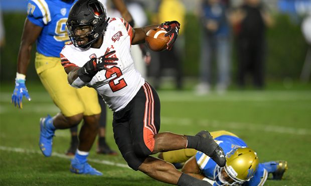 Zack Moss #2 of the Utah Utes runs past Leni Toailoa #26 of the UCLA Bruins in the second half at t...