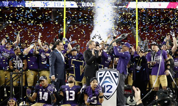 Head coach Chris Petersen of the Washington Huskies is given the championship trophy after the Husk...