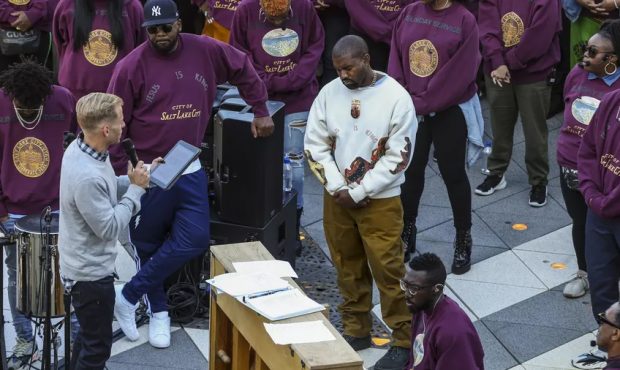 Kanye West, white sweater, bows his head in prayer during his “Sunday Service” at The Gateway i...