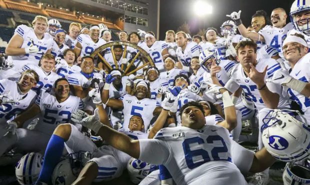 The Brigham Young Cougars pose with the wagon wheel following their 42-14 win over the Utah State A...