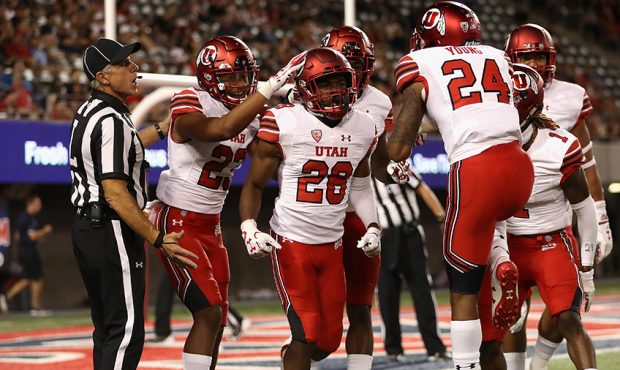 Defensive back Javelin Guidry #28 of the Utah Utes is congratulated by teammates after a 14 yard to...
