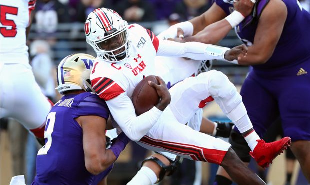 Tyler Huntley #1 of the Utah Utes is sacked by Joe Tryon #9 of the Washington Huskies in the first ...
