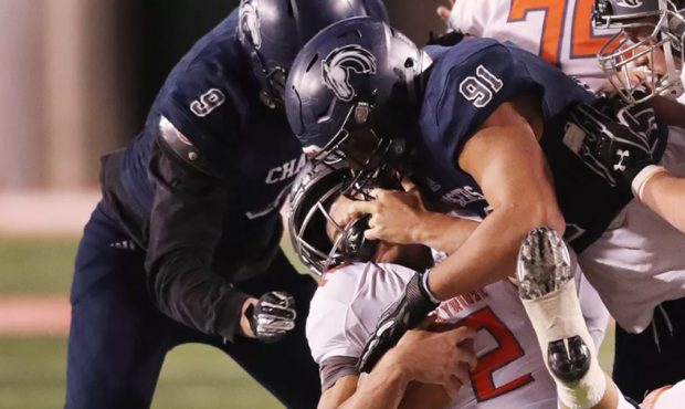 Skyridge QB Jayden Clemons is sacked roughly by Corner Canyon's Van Fillinger during the 5A champio...