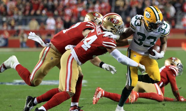 Aaron Jones #33 of the Green Bay Packers is tackled by Fred Warner #54 of the San Francisco 49ers d...