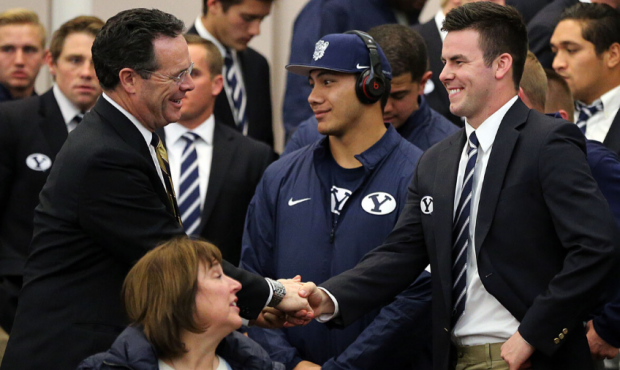 Quarterback Tanner Mangum, center, shakes hands with Brigham Young University Advancement Vice Pres...
