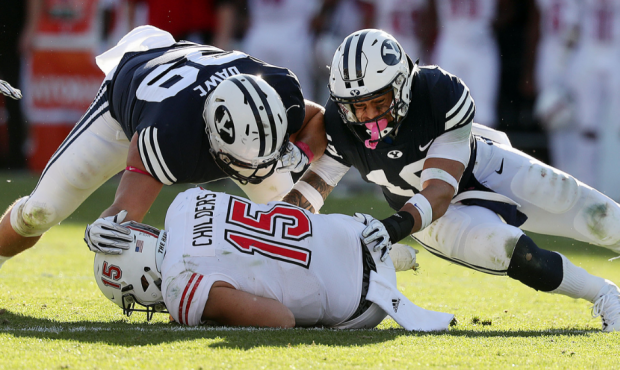 Northern Illinois quarterback Marcus Childers is brought down by BYU defensive lineman Zac Dawe and...