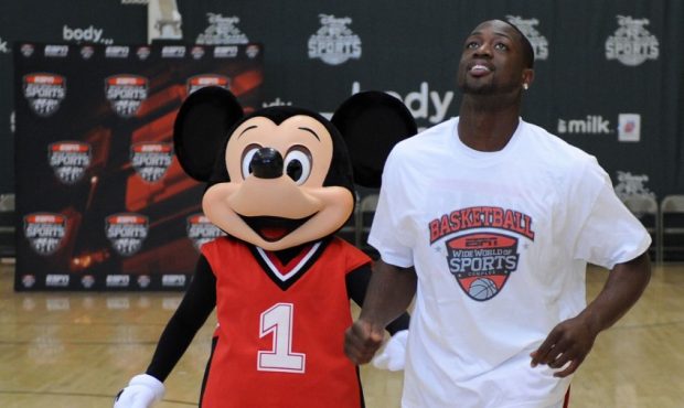 Former NBA guard Dwyane Wade jogs down the court with Mickey Mouse (Photo by Todd Anderson / Disney...