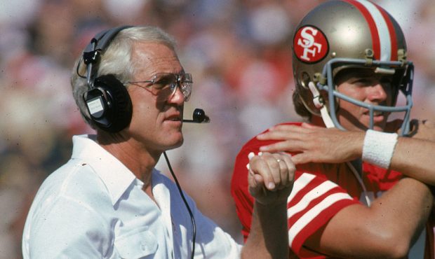 Head coach Bill Walsh of the San Francisco 49ers watches from the sideline next to quarterback Stev...