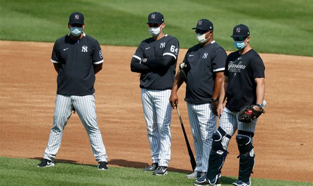 New York Yankee players and coaches stand on the field wearing masks during summer workouts at Yank...