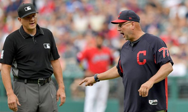 Second base umpire Chad Fairchild listens to Manager Terry Francona #77 of the Cleveland Indians ar...