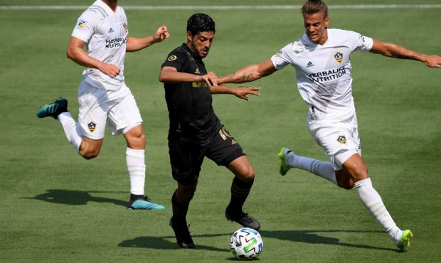 Carlos Vela #10 of Los Angeles FC controls the ball as he is chased by Rolf Feltscher #25 and Perry...
