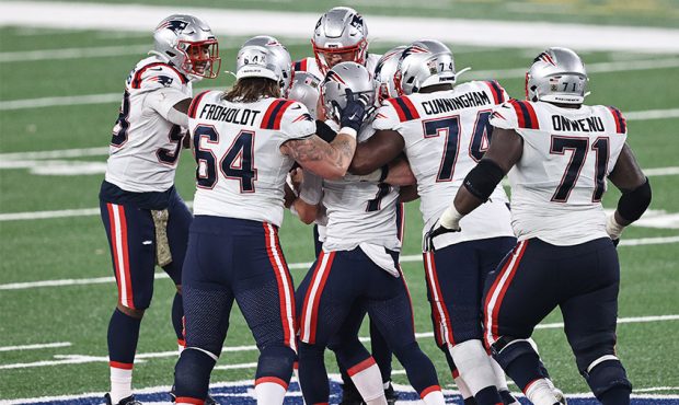 Teammates swarm Nick Folk #6 of the New England Patriots after he kicked the game-winning field goa...