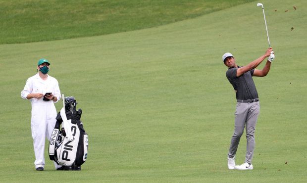 Tony Finau of the United States plays a shot on the second hole as his caddie Mark Urbanek looks on...