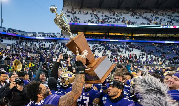 The Washington Huskies including center Nick Henry (56) hold up the Apple Cup trophy after winning ...
