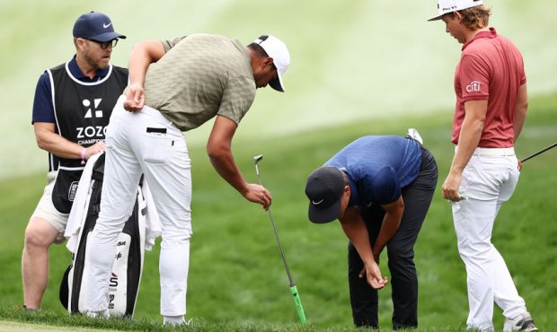 Cameron Champ of the United States inspects his lie on the fifth hole with Tony Finau of the United...