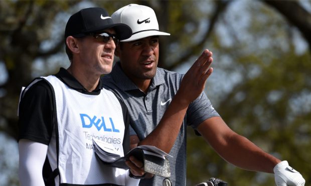 Tony Finau of the United States discusses his shot with his caddie on the first tee in his match ag...