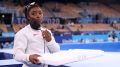 Simone Biles of Team United States supports her team mates by carrying their chalk after pulling out