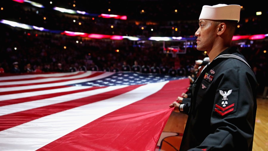 A member of the U.S. Navy holds the American flag before an NBA game (Photo by Jonathan Daniel/Gett...