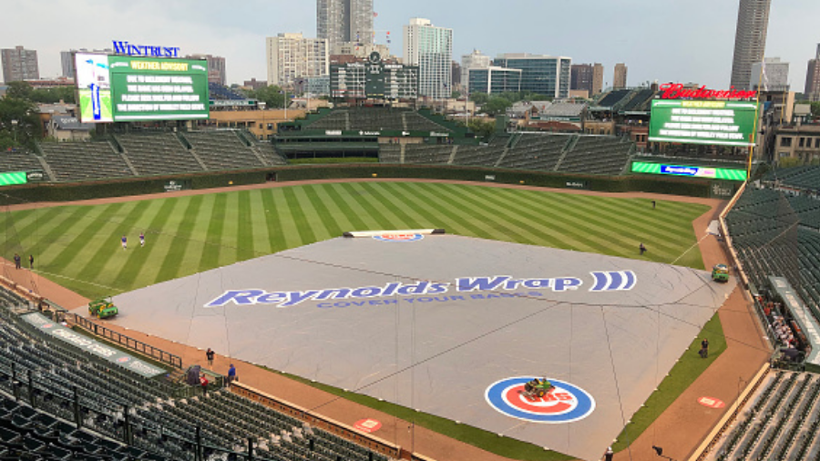 CHICAGO, ILLINOIS - JULY 24: The grounds crew puts on a tarp during a rain delay during the ninth i...