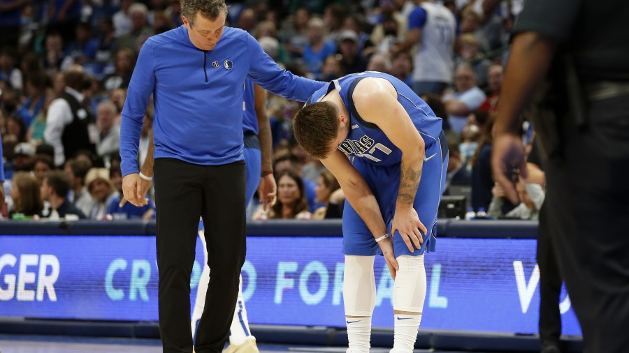 Dallas Mavericks guard Luka Doncic holds his leg after suffering a calf injury (Photo by Tim Heitma...