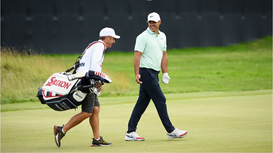 Brooks Koepka of the United States and caddie Ricky Elliott walk the 18th green during the third ro...