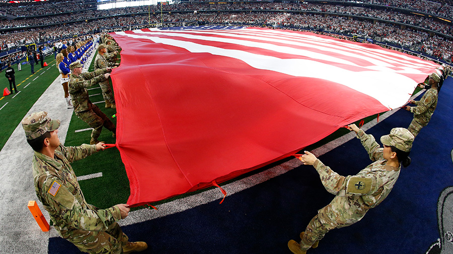military members hold flag on nfl field...