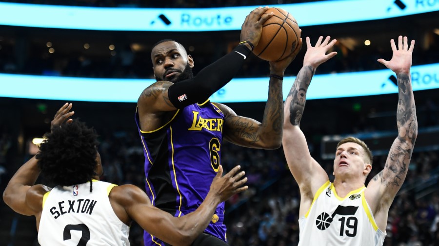 LeBron James #6 of the Los Angeles Lakers looks to pass around Collin Sexton #2 and Luka Samanic #1...