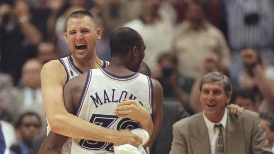 Karl Malone of the Utah Jazz celebrates with teammate Greg Ostertag as head coach Jerry Sloan looks...